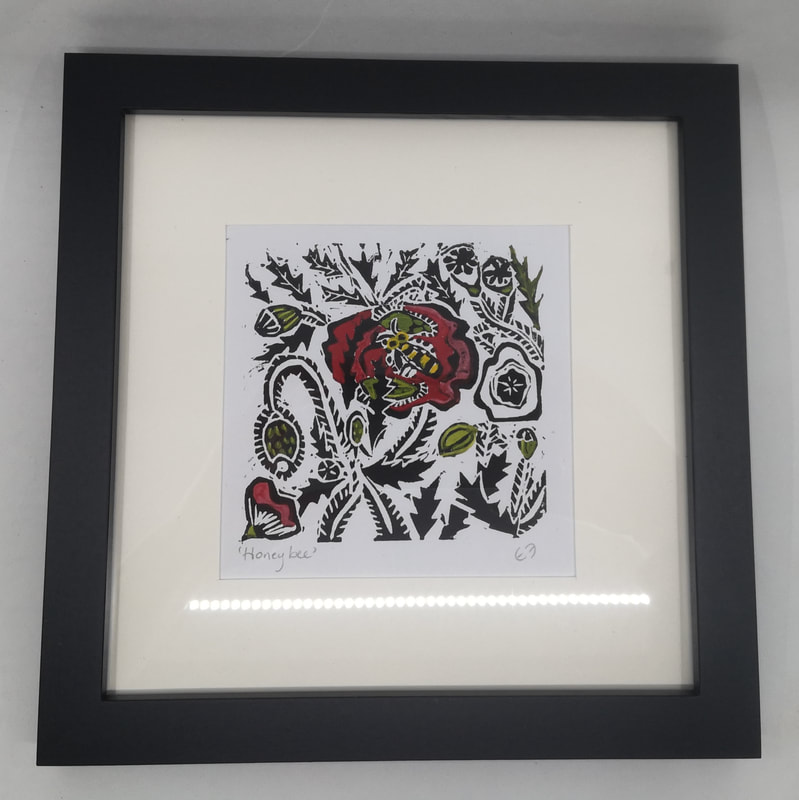 A square framed linocut print featuring a yellow honey bee resting on a red flower surrounded by foliage.