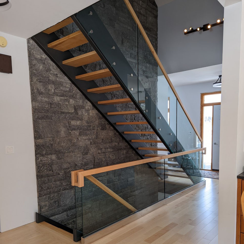 Modern staircase with open, wooden risers, dark stringer and glass railings in a modern home