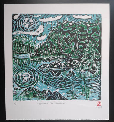 Framed linocut print featuring a forest reflecting on a lake in beautiful hues of blue, green, black and white