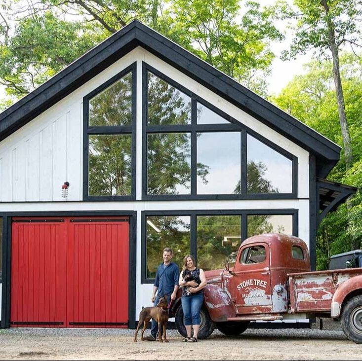 Cirvan, Elise and their two dogs standing and smiling in front of their studio and vintage red truck