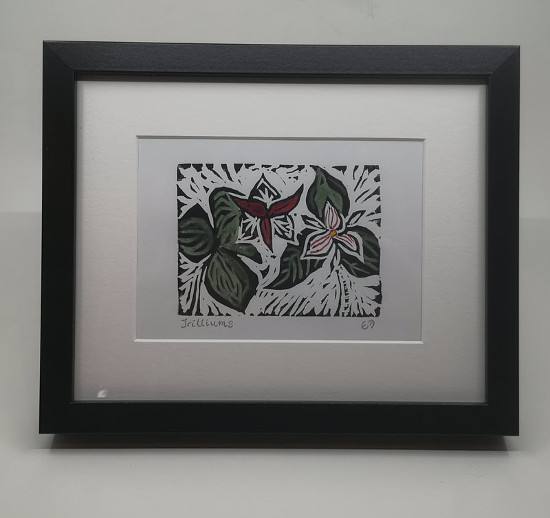 A framed linocut print of colourful trilliums.