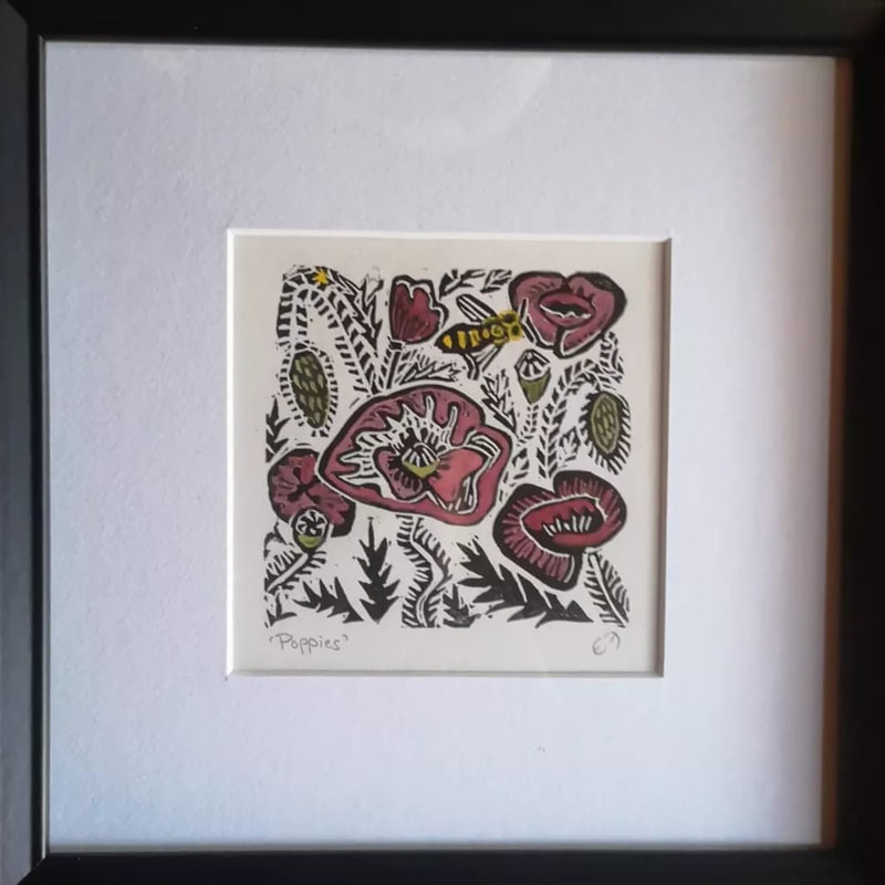 A framed square linocut print featuring red poppies, a yellow bee and foliage all around.