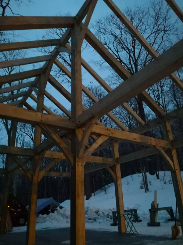 Timber frame in progress at dusk.